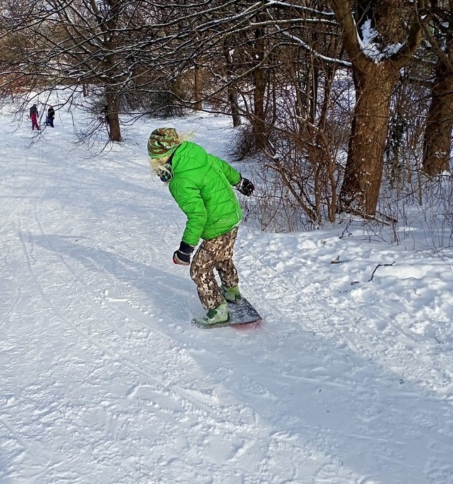 Kind fährt Snowboard auf umgebauten Skateboard